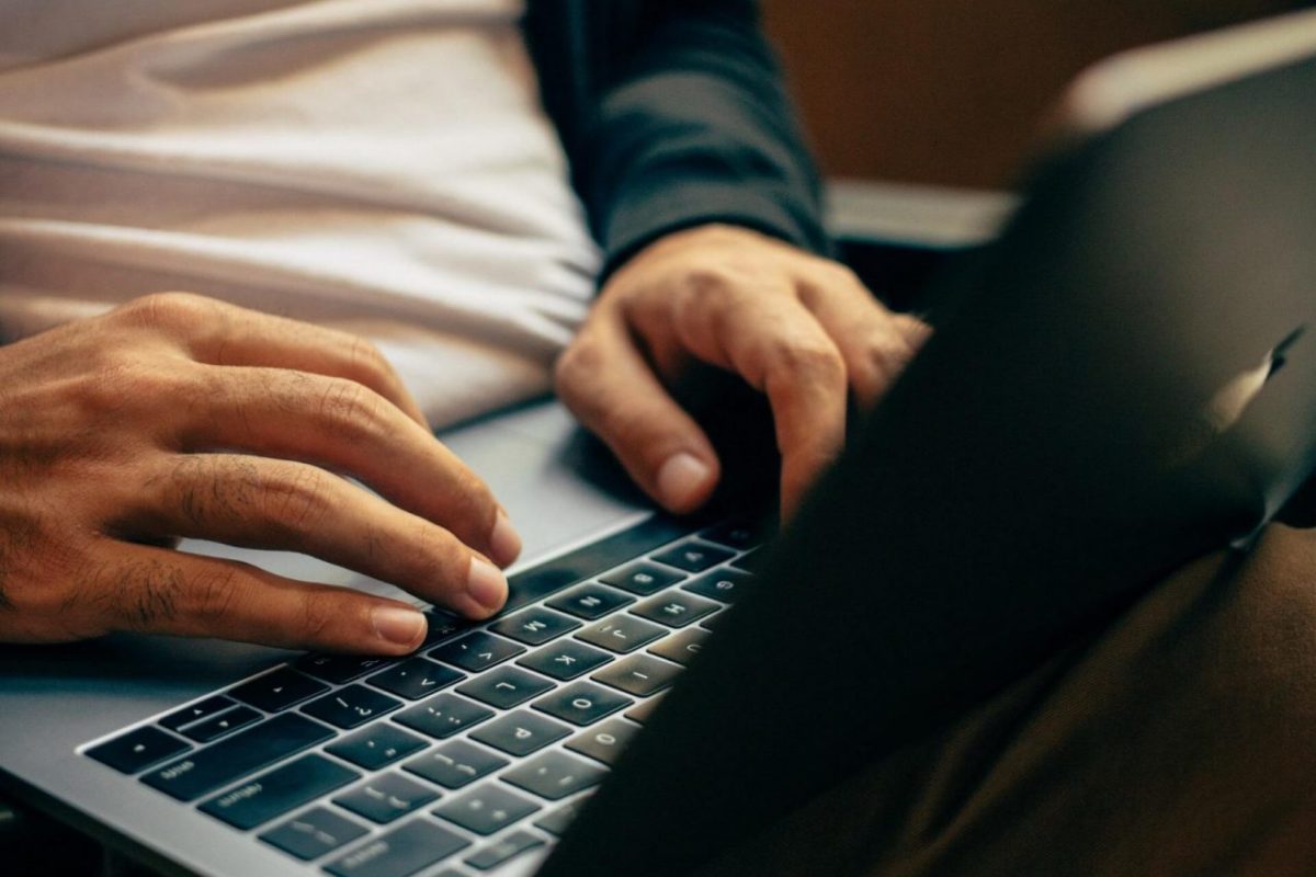 A person working on a laptop on lap while seated